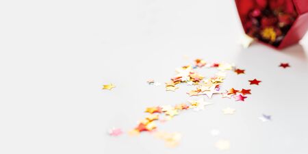 Banner with stars confetti which fallen from red sparkling box. Holiday decoration on white background.の写真素材
