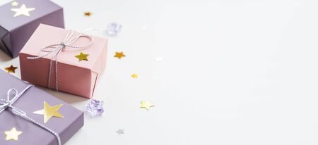 Banner with holiday presents. Gifts wrapped in pale pink and violet paper with silver ribbons and bow. Stars confetti and white copy space.の写真素材