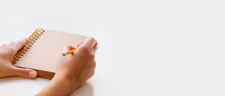 Woman is preparing to write or draw something in notepad with craft paper pages. Banner with copy...