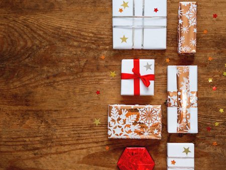 Christmas presents on shabby wooden background. Gifts in white and golden paper with bright golden...