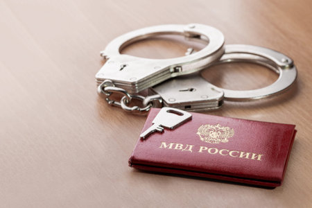 Locked handcuffs with key and certificate of employee of the Ministry of internal Affairs. Concept...