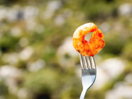 Mediterranean cuisine - freshly roasted shrimp on fork. Seafood on green foliage background. Outdoor...