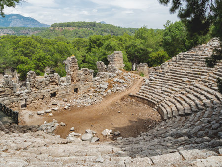 Tourists walk into ruins of amphitheatre of ancient Phaselis city. Panorama view on famous...