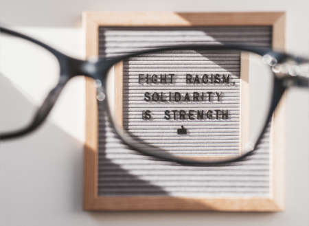Top view on letter board with words Fight Racism, Solidarity is Strength through eyeglasses. Flat lay concept with actual statement. Social issue. Closer look on race problem in society.の写真素材