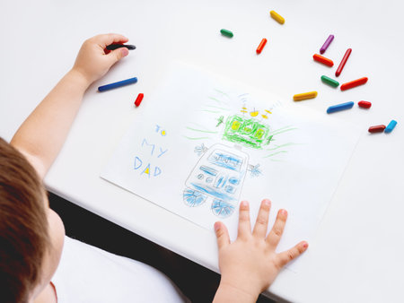 Left-handed toddler draws greeting card with funny robot for Father's day or Daddy's Birthday. Kid...