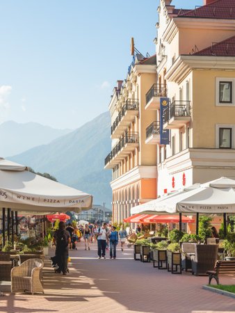 SOCHI, RUSSIA - October 13, 2018. Mzymta river embankment in Rosa Dolina. Famous Rosa Khutor Alpine Ski Resort near Sochi. Tourists walk pass Tulip Inn.のeditorial素材