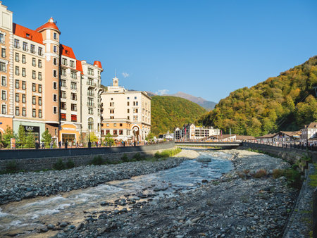 SOCHI, RUSSIA - October 13, 2018. Mzymta river embankment in Rosa Dolina. Famous Rosa Khutor Alpine Ski Resort near Sochi. Tourists walk near Golden Tulip hotel.のeditorial素材