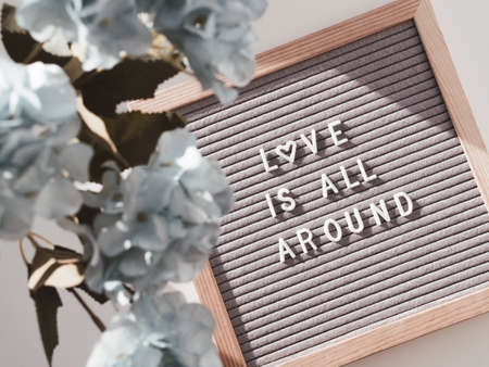 Top view on letter board with words LOVE IS ALL AROUND. Flat lay concept heart symbol of love and romance. Blue hydrangea flowers.の写真素材