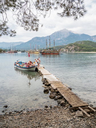 PHASELIS, TURKEY - May 19, 2018. Tourists get into the boat after excursion. Touristic yachts and boats in harbor of ancient ruins of Phaselis city.のeditorial素材