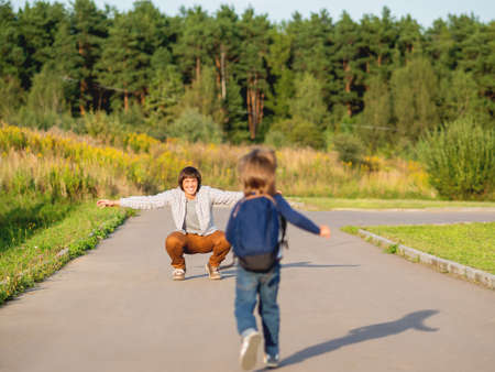 Father picks up his son from kindergarten. Back to school after summer holidays. Family time, moral support.の写真素材