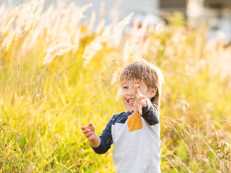 Cute toddler plays in field. Smiling boy throws plant seeds in the air. Autumn outdoor leisure activity for children. Fall season.の写真素材