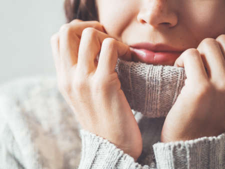 Close up portrait of woman snuggling in warm gray sweater. Casual outfit for cold weather at winter season.の写真素材
