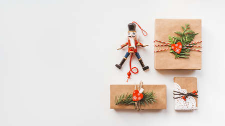 Christmas DIY presents wrapped in craft paper and wooden Nutcracker toy. Decorations on New Year gifts. Festive background. Winter holiday spirit. White background with copy space.の写真素材