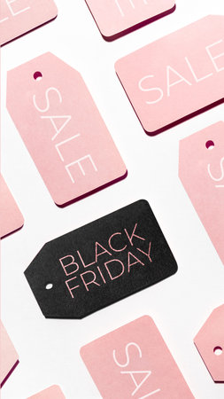 Top view on pattern of many pink and one black clothes tags on white background. Glamorous labels....