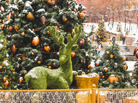 Christmas tree with golden and bronze balls and reindeer made of artificial grass. Outdoor decorations for New Year celebration. Moscow, Russia.の写真素材