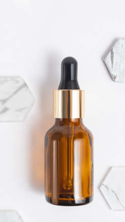 Top view on glass bottles of essential oil or cosmetic serum on white background. Decorative marble and glass hexagons.の写真素材