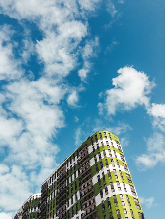 Colorful modern apartment building on blue sky background. Bottom view on skyscraper with green stripes in sunny day.の写真素材