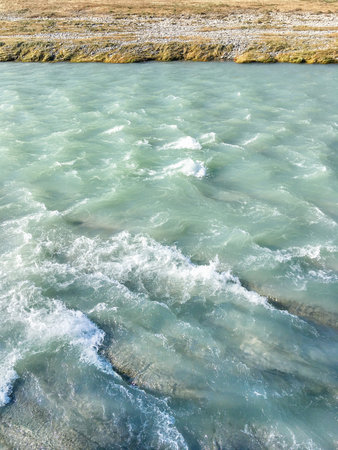 Turquoise waters with white foam and bank with grass of Sochi river .. Mountain river with clear...