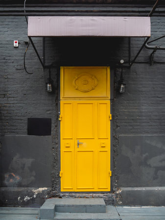 Building with black brick walls and bright yellow door. Colorful urban background.の写真素材