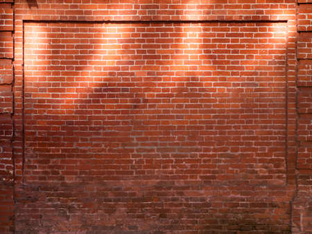 Red brick wall with sunbeams. Old wall with sun reflections at upper part. Old building with shabby surface. Mock up.の写真素材