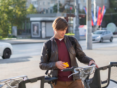 Young man is renting bicycle by smartphone application. Eco-friendly urban transport for rent....