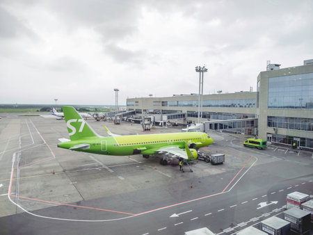 MOSCOW, RUSSIA - June 28, 2021. Green airplane of S7 Airlines company parked in Domodedovo airport. View on airfield through window.のeditorial素材