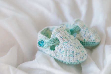 Crocheted first booties for baby. Handmade shoes for newborn boy or girl. Cute accessory on white...