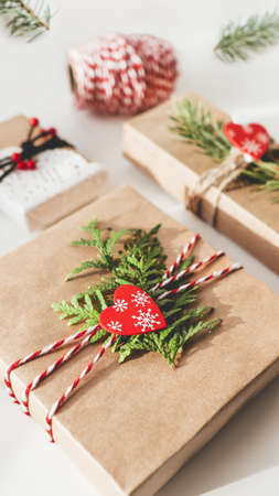 Christmas DIY presents wrapped in craft paper with fir tree branches and red hearts. Decorations on New Year gifts. Festive background. Winter holiday spirit.の写真素材