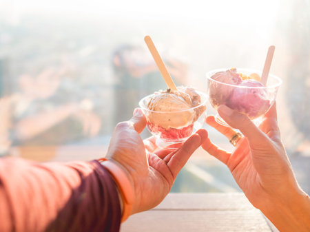 Man and woman holds plastic bowls with colorful balls of ice-cream. Cold dessert for sunny days....