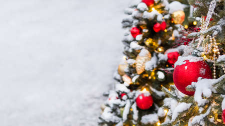Christmas tree with colorful outdoor decorations. Fir tree decorated with light bulbs for New Year celebration. Banner with copy space.の写真素材