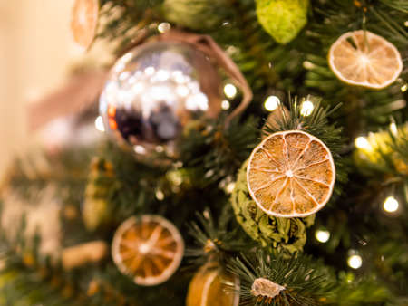 Christmas tree with dried lemons and natural decorations. Fir tree decorated with light bulbs and shiny balls for New Year celebration.の写真素材