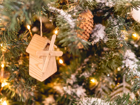 Christmas tree with wooden vintage decorations. Fir tree decorated with light bulbs and toy windmill for New Year celebration.の写真素材