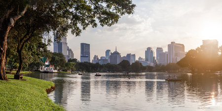 BANGKOK, THAILAND - October 23, 2012. Panorama of downtown skyscrapers from Lumpini park. Sunset view over pond in recreation park.のeditorial素材
