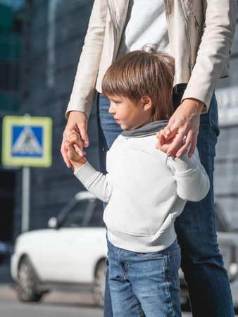 mother and son stand on street in sunlight. Woman and kid in modern town with transport traffic and road sign. family in city.の写真素材