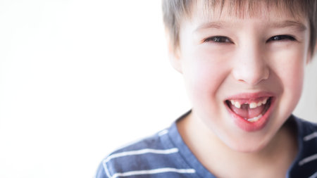 Smiling kid shows hole in row of teeth in his mouth. One incisor fell out just now. Close up photo...