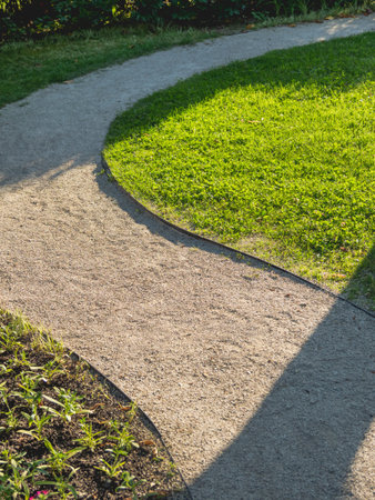 Walking path winding among lawns in garden. Landscaping in the park.