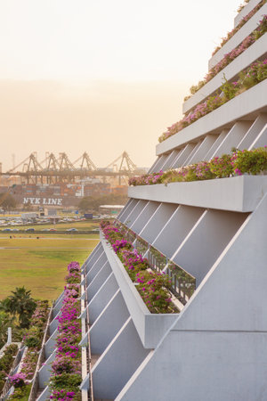 SINGAPORE, SINGAPORE - January 17, 2013. Balconies with decorative flowers of Marina Bay Sands and cargo cranes of sea port.のeditorial素材