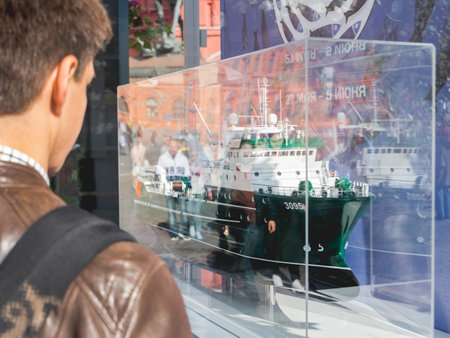 MOSCOW, RUSSIA - May 29, 2022. Man is looking on model of industrial fishing boat. Exhibition on outdoor food festival Fish Week.のeditorial素材