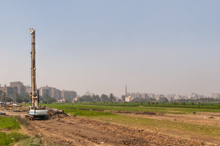 GIZA, EGYPT - September 11, 2008. Construction site with working pile driver in Giza. Urban skyline with silhouette of Big Pyramid.のeditorial素材