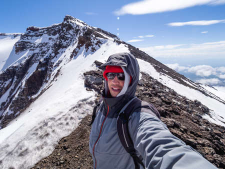 Man makes selfie on caldera of Plosky Tolbachik stratovolcano. Hiking in the mountains. Natural landmark of Kamchatka Peninsula. Russia.の写真素材
