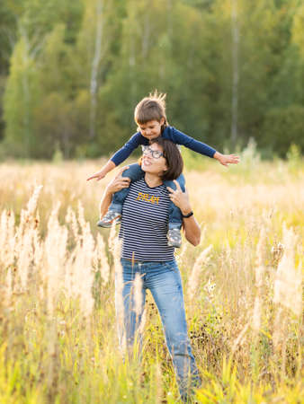 Cute boy and his mother play with toy air plane. Happy kid dreams to be a pilot. Boy is planning for the future. Mom and son on the field at autumn season.の写真素材