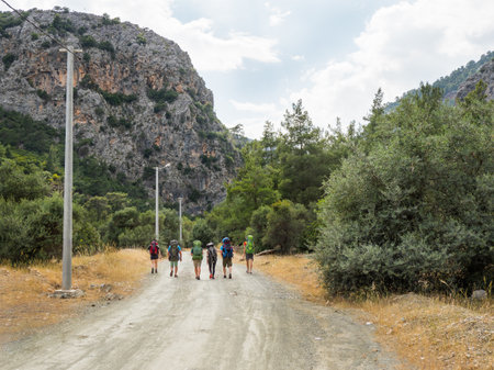 Tourists with backpacks walk to Goynuk Canyon. Path along mountain slopes in Beydaglari Coastal National Park. Turkey.の写真素材