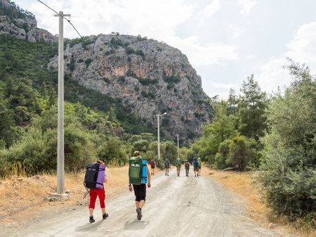 Tourists with backpacks walk to Goynuk Canyon. Path along mountain slopes in Beydaglari Coastal National Park. Turkey.の写真素材