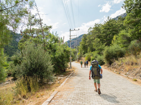 Tourists with backpacks walk to Goynuk Canyon. Cobble way along mountain slopes in Beydaglari Coastal National Park. Turkey.の写真素材