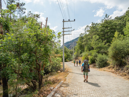 Tourists with backpacks walk to Goynuk Canyon. Cobble way along mountain slopes in Beydaglari Coastal National Park. Turkey.の写真素材