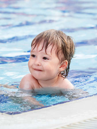Toddler floats in paddling pool. Teaching children to swim from early childhood. Sport, active lifestyle and physical development.の写真素材