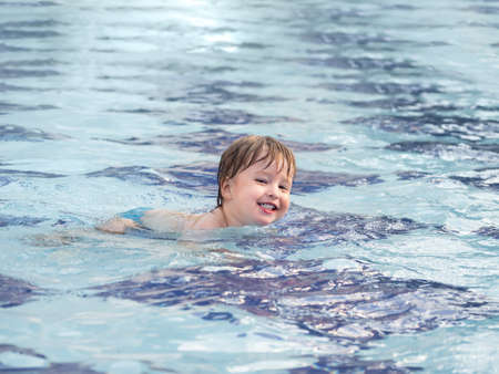 Toddler floats in paddling pool. Teaching children to swim from early childhood. Sport, active lifestyle and physical development.の写真素材