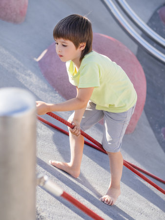Boy climbes up a concrete slope of modern children's sports and playground. Kid overcomes fear and learn new things. Active leisure outdoors. sport lifestyle.の写真素材