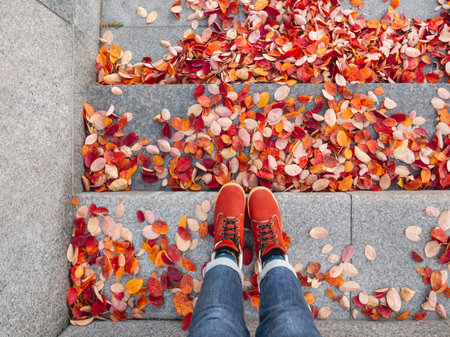 Top view on feet in red leather shoes. Woman is standing on stone street steps with bright red...