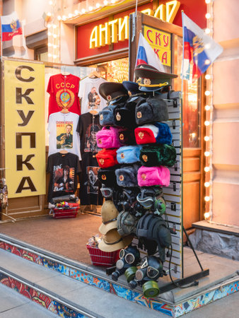 MOSCOW, RUSSIA - October 16, 2022. Souvenir shop on Arbat street. Sale of colorful furry military hats with old USSR emblem, t-shirts with prints and quotes.のeditorial素材